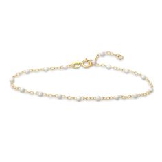 Distinctive white enamel beads embellish shimmering links around the length of this stylish women's bracelet. Fashioned in 14K yellow gold, the 7.5-inch cable chain secures in place with a spring ring clasp. Dainty White Beaded Bracelets With Adjustable Chain, Dainty White Jewelry With Gold Chain, White Gold Beaded Chain Jewelry, White Dainty Bracelets With Adjustable Chain, White Beaded Chain Pearl Bracelet Gift, Adjustable 14k Gold White Bracelet, White Pearl Chain Bracelet Gift, White Pearl Bracelet With Beaded Chain, White Dainty Chain Bracelet With Round Beads