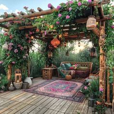 an outdoor living area with lots of flowers and plants on the roof, couches and rugs