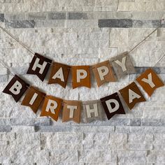 a happy birthday banner hanging on a brick wall with the words happy birthday spelled in wood letters