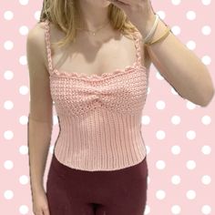 a woman taking a selfie in front of a pink polka dot background with her cell phone