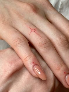 two hands with red nail polish on them and one has a cross drawn on it