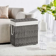 a wicker storage box sitting on top of a white rug next to a couch