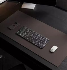 a black desk with a keyboard and mouse on it, next to a computer monitor