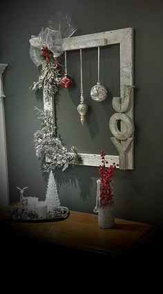 an old window frame with ornaments hanging from it and a candle holder on the table