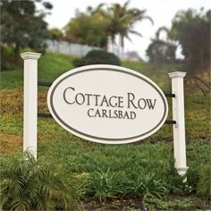 a white sign that reads cottage row carlisle road in front of some bushes and trees