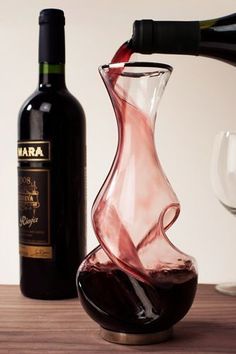 a bottle of wine is being poured into a glass next to a decanter