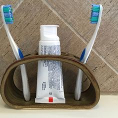 two toothbrushes are in a holder with toothpaste on it's sides