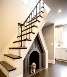 a dog is sitting in his house under the stairs