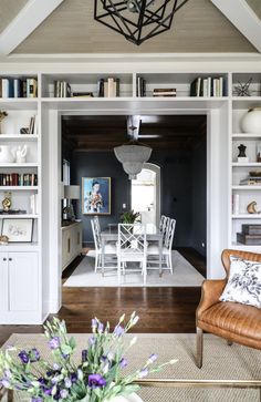 a living room filled with furniture and bookshelves next to a dining room table