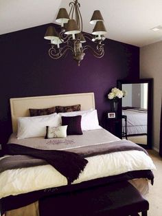 a bedroom with purple walls and white bedding, chandelier above the bed