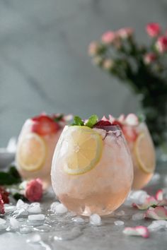 two glasses filled with lemonade and garnished with strawberries on the table