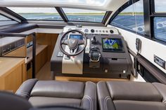 the inside of a boat with leather seats and steering wheel, on which there is an entertainment center