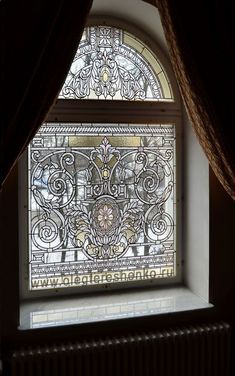 a stained glass window in the corner of a room with curtains on either side and below it