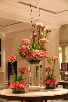 there are many flowers in the vases on the counter top, and one is pink