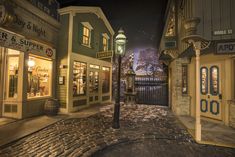 an empty street at night with shops on both sides