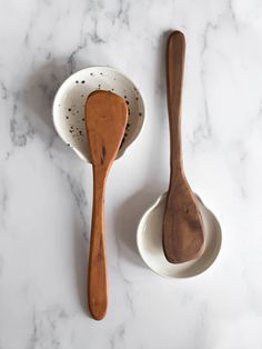 two wooden spoons sitting next to each other on a marble counter top with white and black speckles