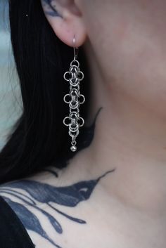 a close up of a person with tattoos on their chest and wearing large silver earrings