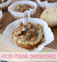 some cupcakes that are sitting on top of a wooden table with the words pecan pralie cheesecakes