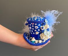 DreamsHead presents its novelty Micro Mini hat tea party It is adorned with mini flowers, mini cups, a mini cake and a teapot-shaped fibula The hat is covered with a blue fabric with small teapots, a navy blue satin ribbon and a navy blue stripe Completely handmade by me Height size 7.62cm and 10cm wide The color of the item may differ from your screen due to variance in computer monitors The hats hold on the head by a rubber band, to pass through the back of the head up to the nape of the neck Tea Hat, Alice In Wonderland Mad Hatter, Wonderland Mad Hatter, Hat Tea Party, Tea Hats, Mad Hatter Hat, Mini Hat, Holiday Hats, Mini Top Hat