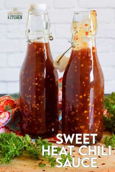 two glass bottles filled with sauce sitting on top of a wooden cutting board next to parsley