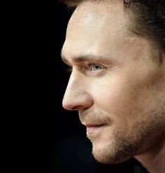 a close up of a person wearing a suit and tie with his hair in a bun