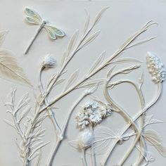 some flowers and dragonflies on a white surface