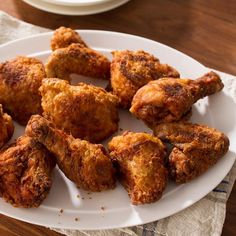 some fried food on a white plate next to a glass of milk and a cup