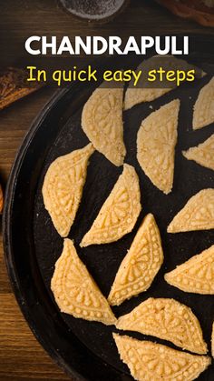 a pan filled with cut up pieces of food on top of a wooden table next to bread