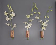 three vases with flowers are hanging on the wall