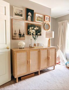 a living room with pictures on the wall and flowers in vases sitting on top of it