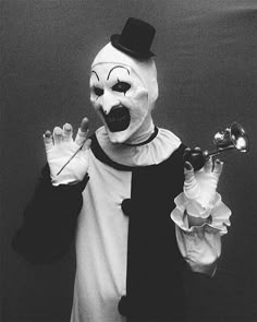 a person wearing a clown mask and holding two bells