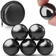 black balls are shown in front of a zippered pouch and one is being held by a hand