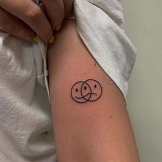 a woman's arm with a tattoo on it that has two circles in the middle