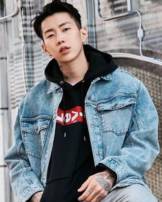 a young man sitting on top of a metal bench wearing a denim jacket and black t - shirt