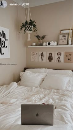 a laptop computer sitting on top of a bed in a room with white sheets and pillows