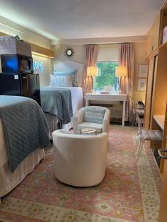 a bedroom with two beds, a chair and a desk in the middle of it