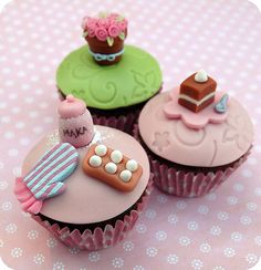 three decorated cupcakes sitting on top of a table