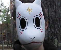 a man wearing a white mask with black eyes and nose painted to look like a cat