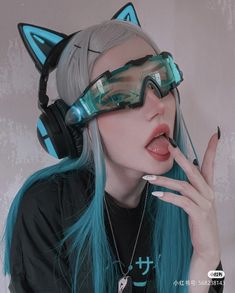 a woman with blue hair and cat ears wearing headphones on her face is posing for the camera