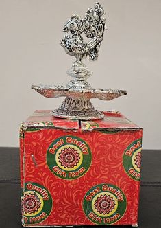 a silver trophy sitting on top of a red and yellow box with designs around it