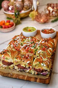 a wooden cutting board topped with a cut in half sandwich next to bowls of salsa and guacamole