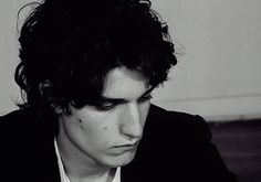 black and white photograph of a young man looking at his cell phone while wearing a suit