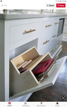 an open drawer on the side of a kitchen counter with papers and pencils in it