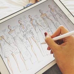 a person is drawing on an ipad with a pen and paper in front of them