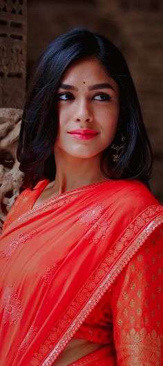 a woman in an orange sari posing for the camera