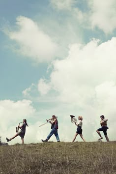 a group of people walking across a grass covered field