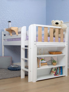 a white bunk bed sitting next to a book shelf on top of a wooden floor