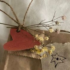 a brown paper bag with some flowers and a red heart shaped tag attached to it