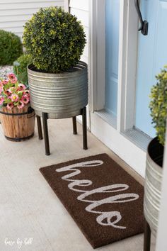 a welcome mat on the front porch with potted plants