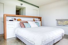 a bed with white sheets and pillows in a room